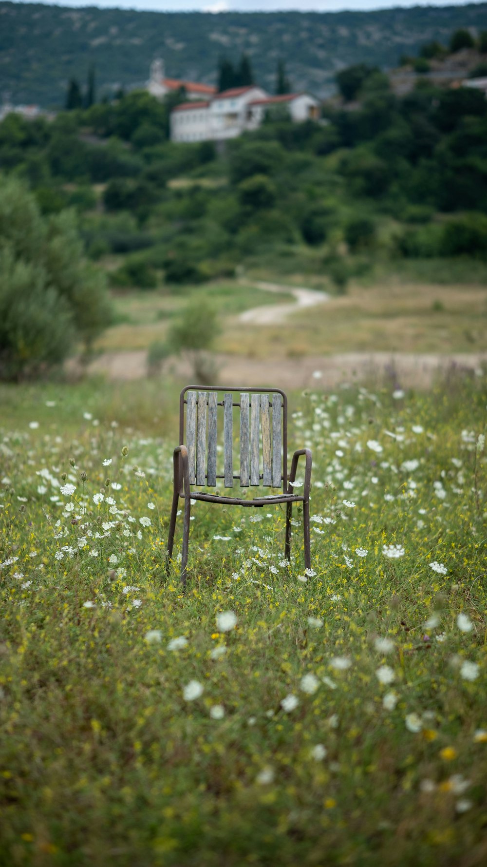 a wooden chair sitting in the middle of a field