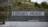 A hillside sports area with a concrete wall displaying the text 'Torcida Ricice' in bold letters. The surroundings include greenery and rocks, suggesting a natural backdrop. The area seems to be an outdoor sports field with metal fencing and a white, weathered soccer goal.
