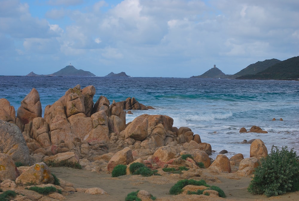 a rocky beach with a body of water in the background