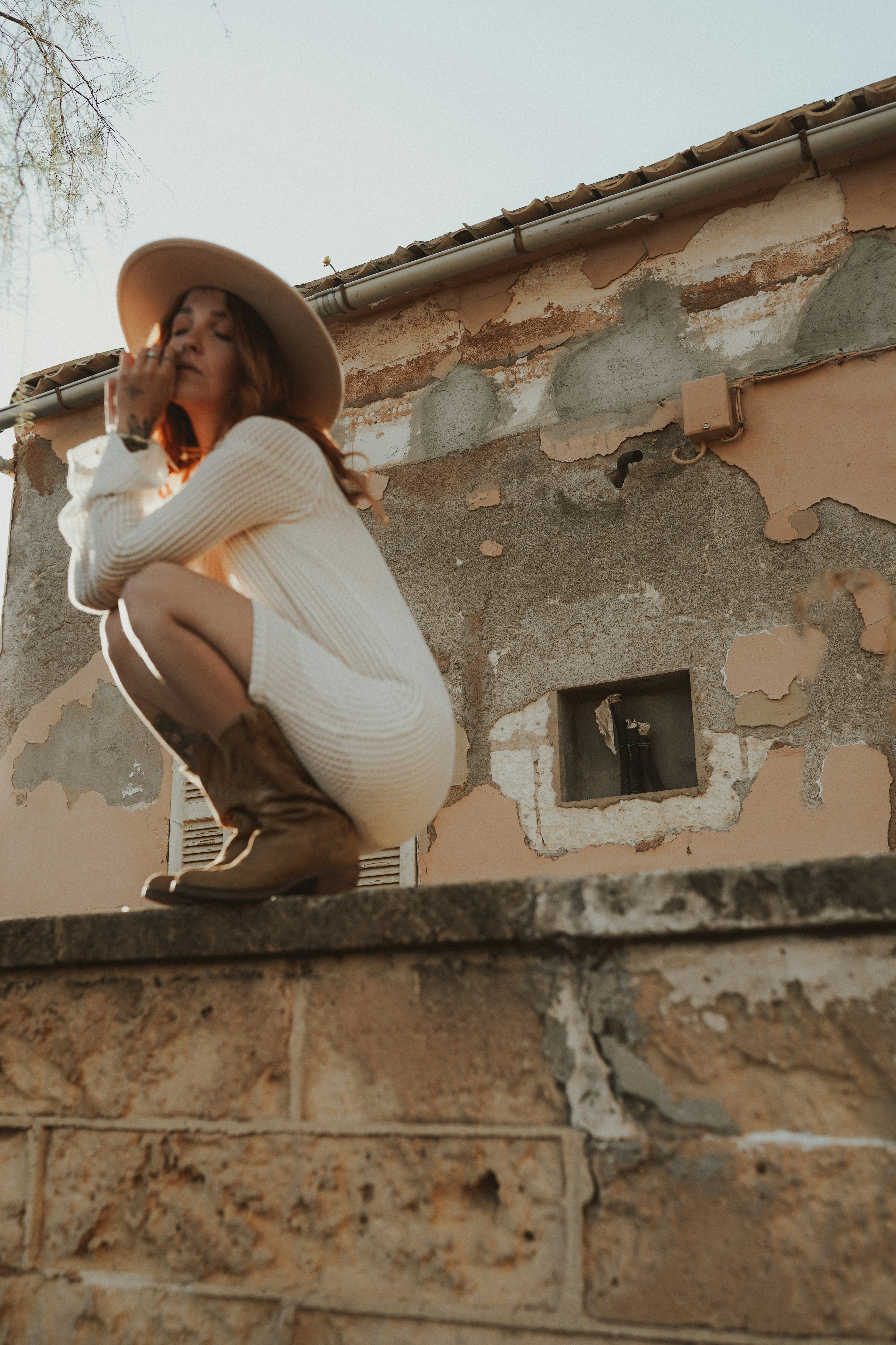 Una mujer sentada en una pared con un sombrero puesto foto – Imagen de ...
