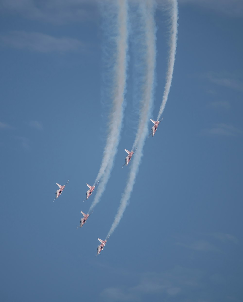 a group of jets flying through a blue sky