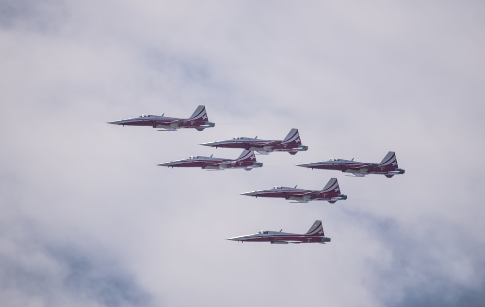 a group of fighter jets flying through a cloudy sky