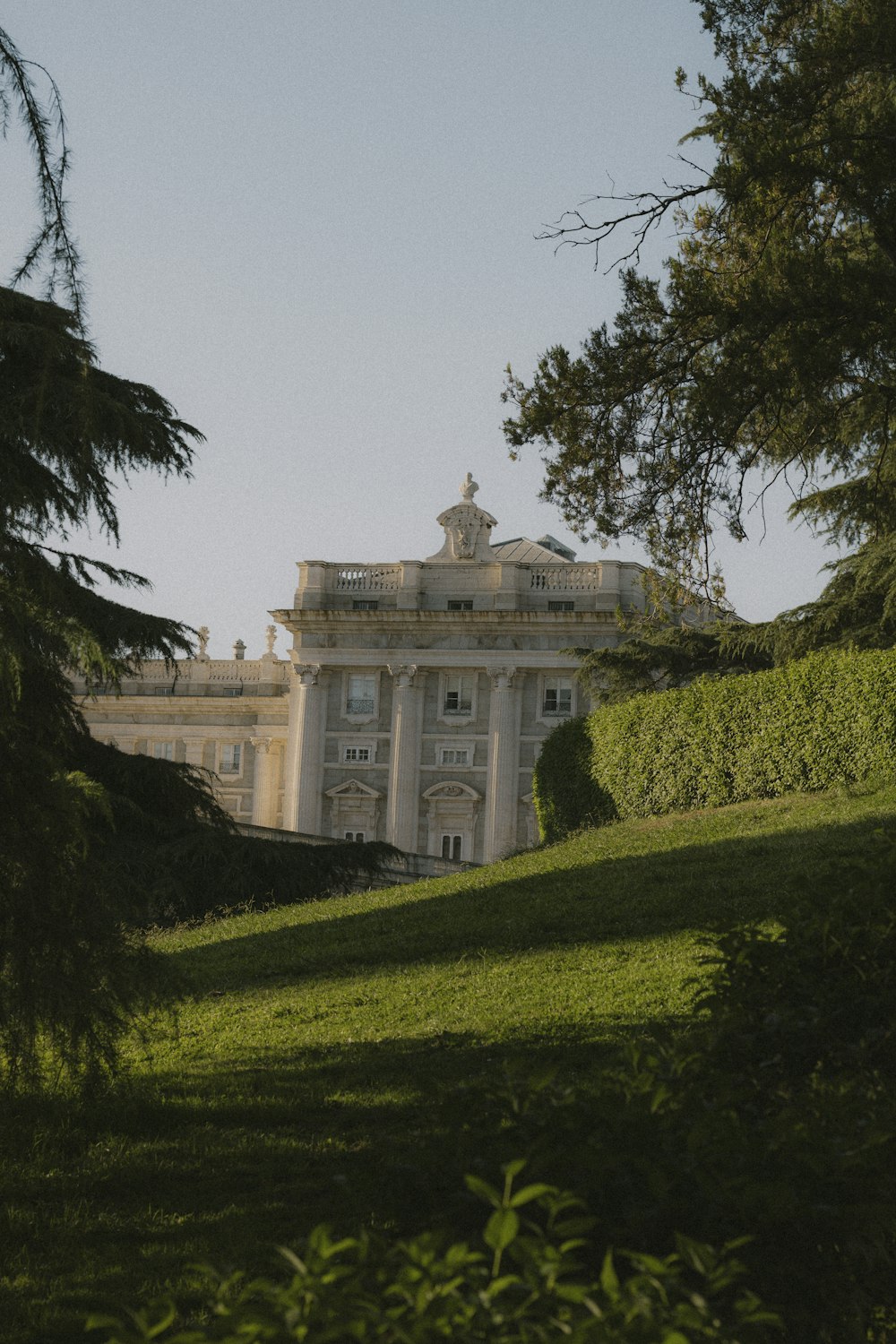 a large white building sitting on top of a lush green hillside