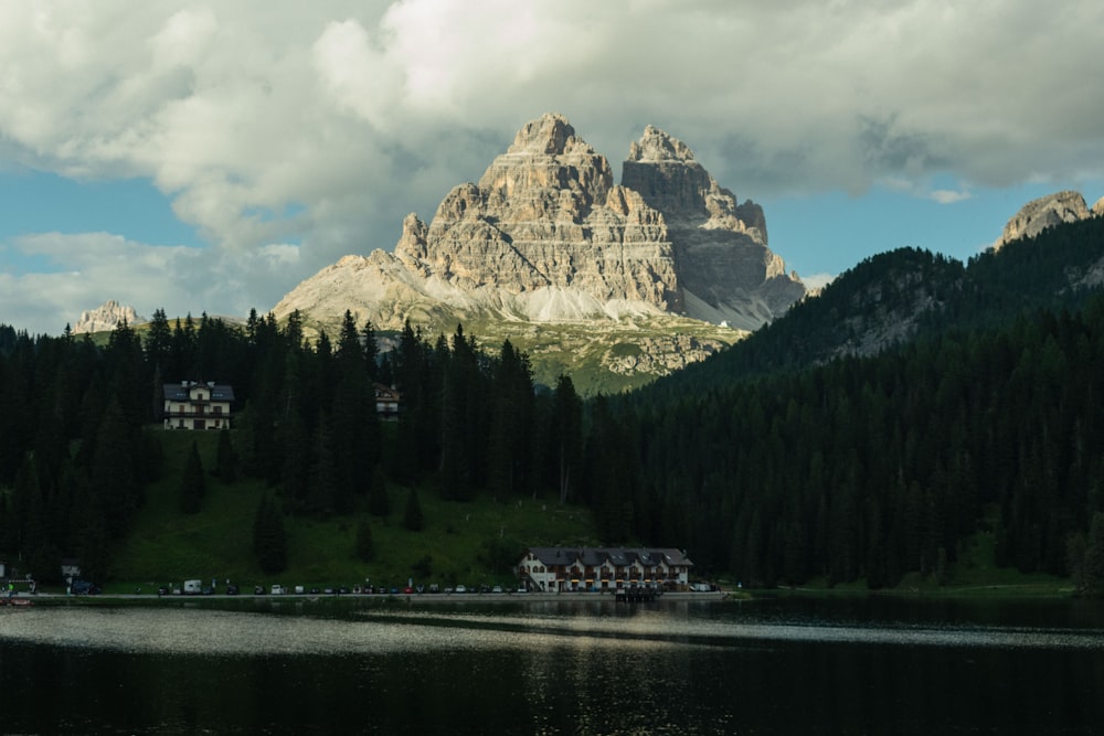 a lake surrounded by trees and mountains under a cloudy sky