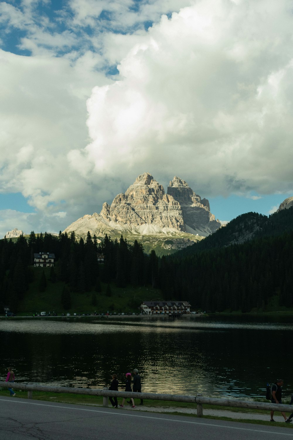 a group of people walking along a road next to a lake