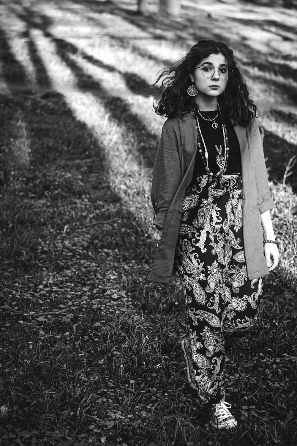 a woman standing in the grass in front of a tree