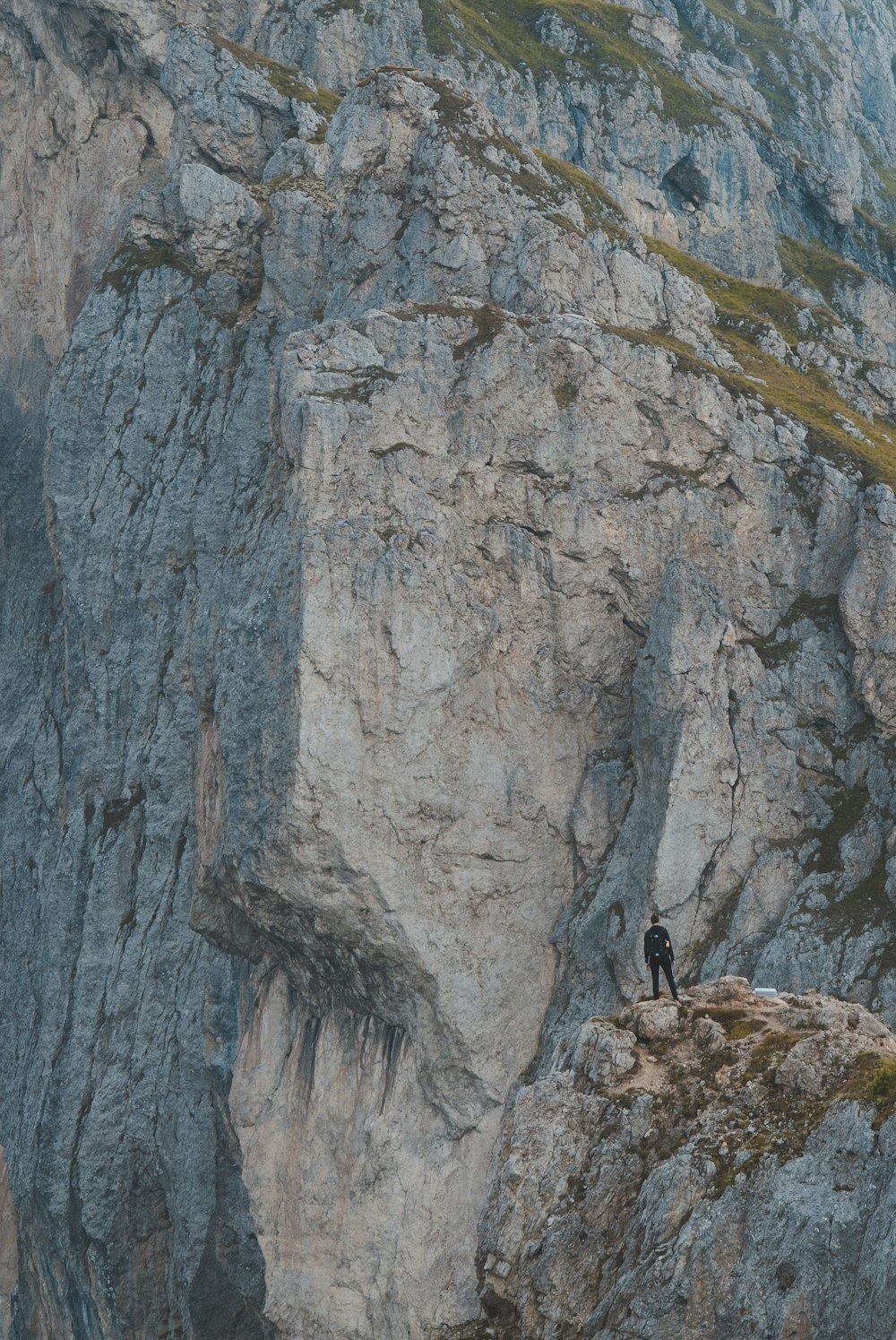 a person standing on top of a mountain next to a cliff