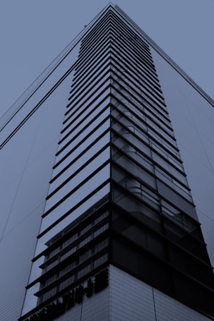 A modern high-rise building with a sleek, geometric design featuring horizontal and vertical lines. The facade has a combination of glass and metal elements, creating a reflective and structured appearance.