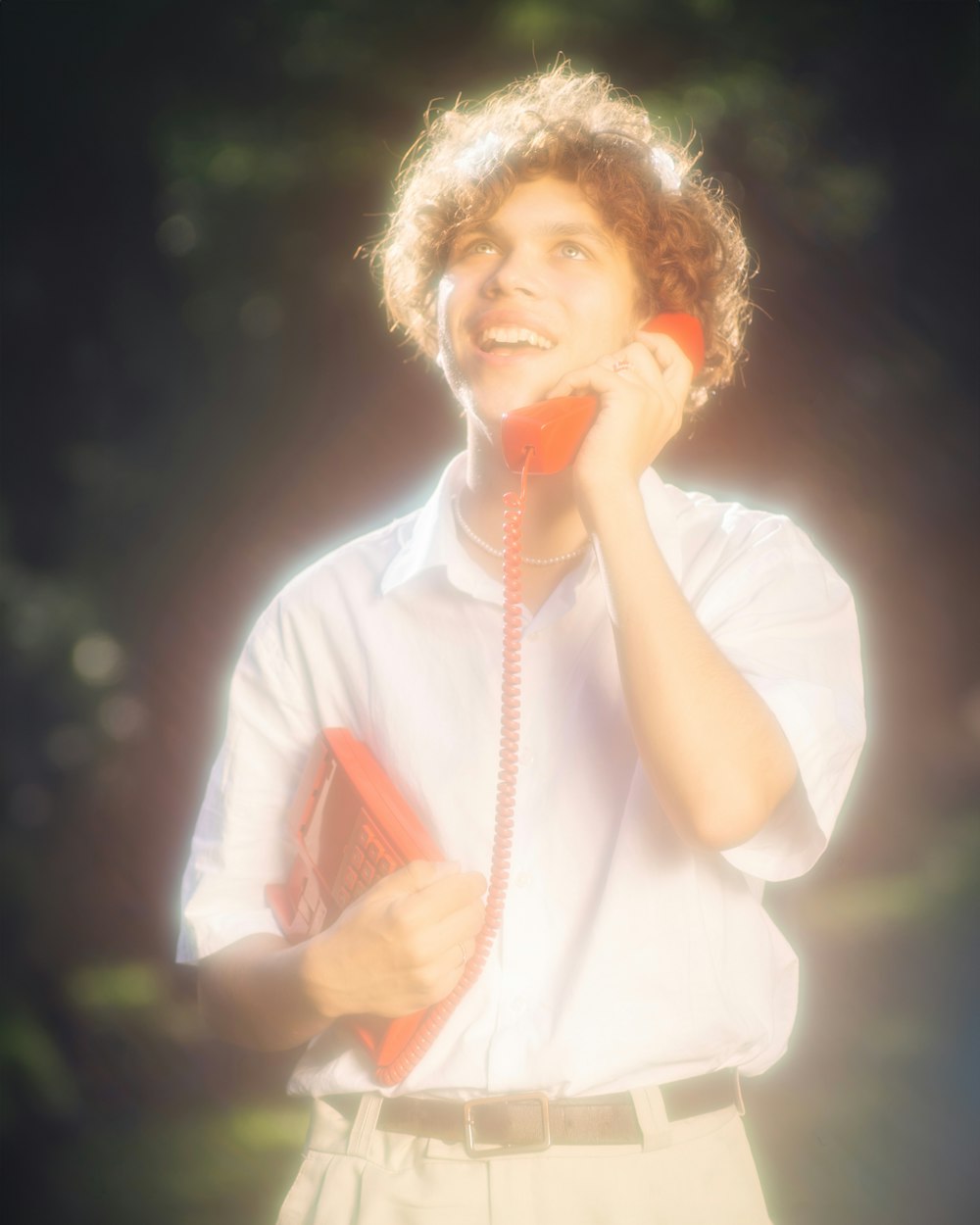 a young man talking on a red phone