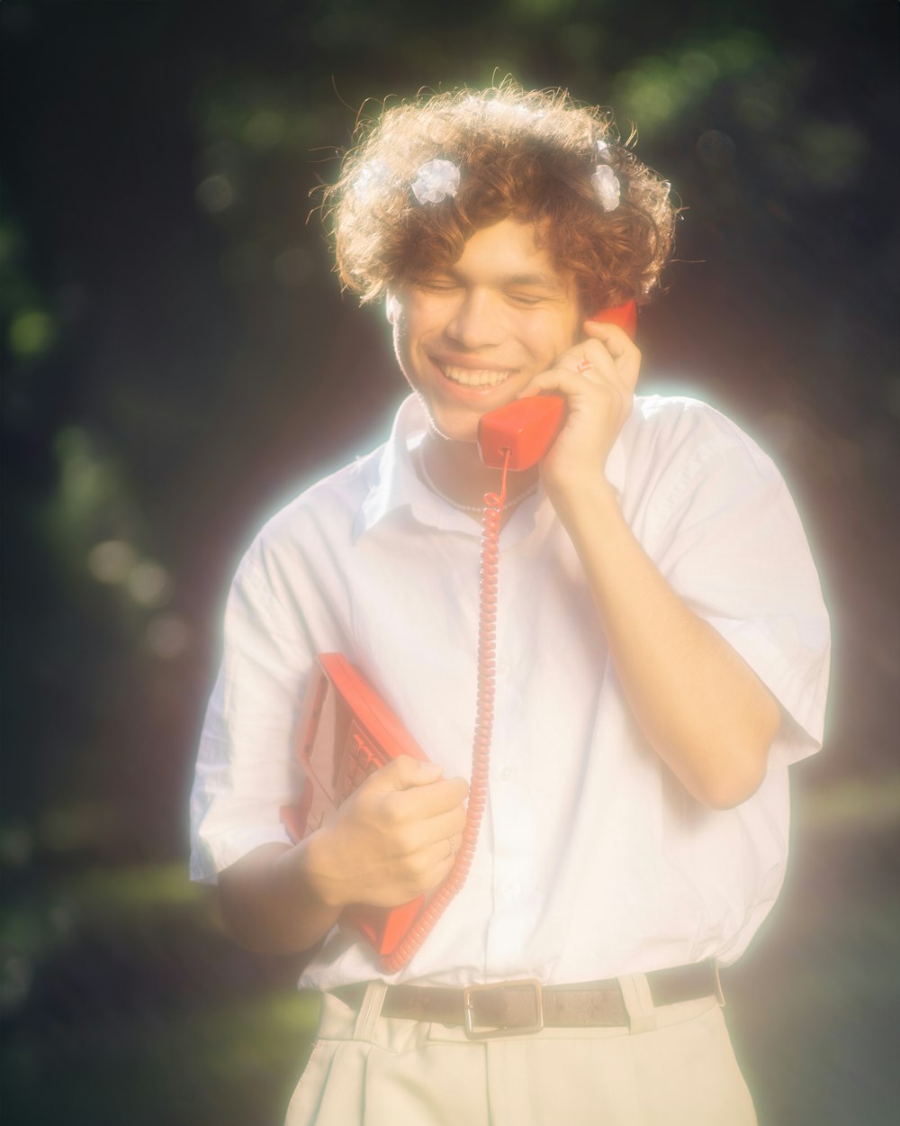 a young man holding a red phone to his ear