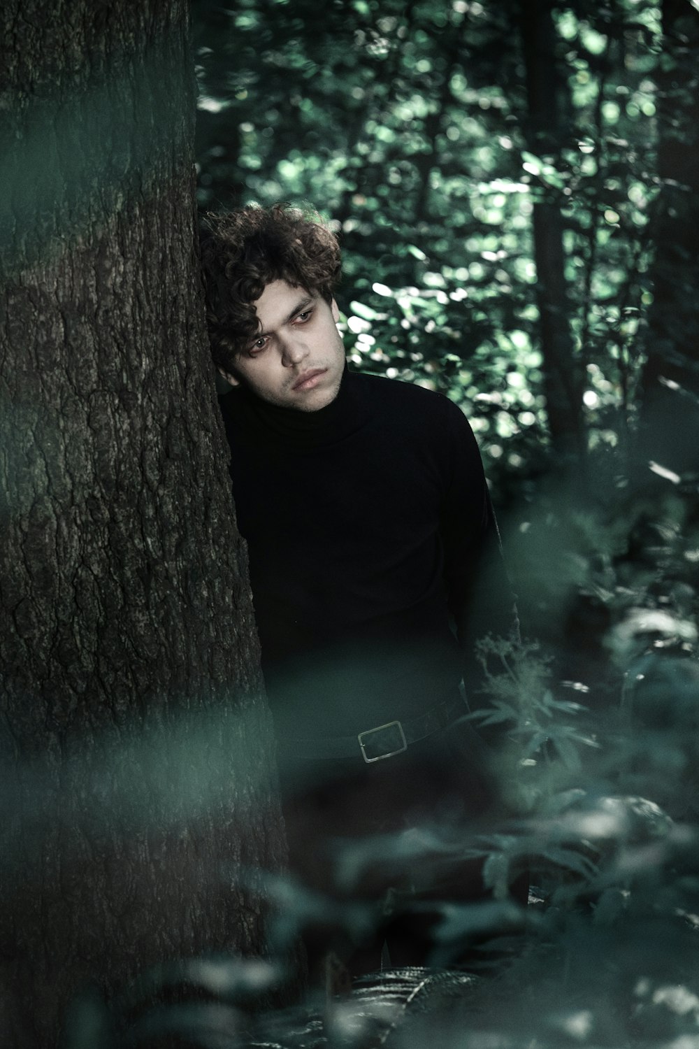 a man standing next to a tree in a forest