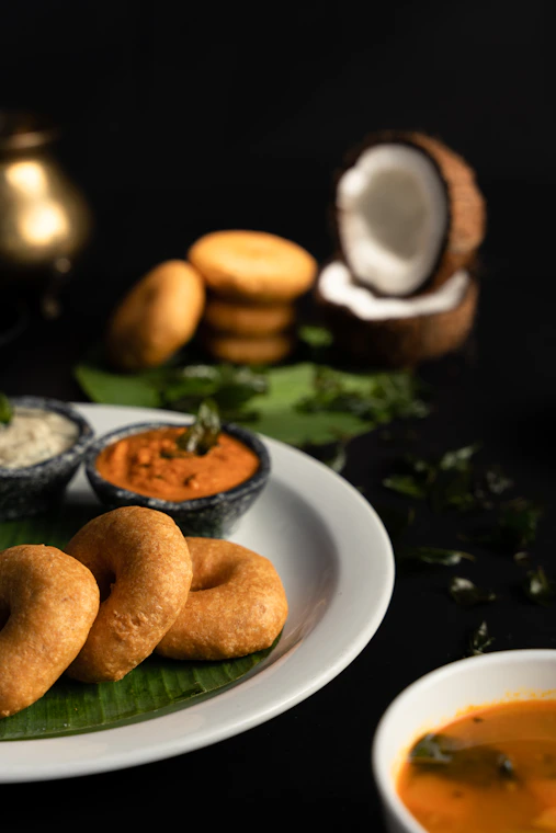 a white plate topped with doughnuts next to bowls of dipping sauce