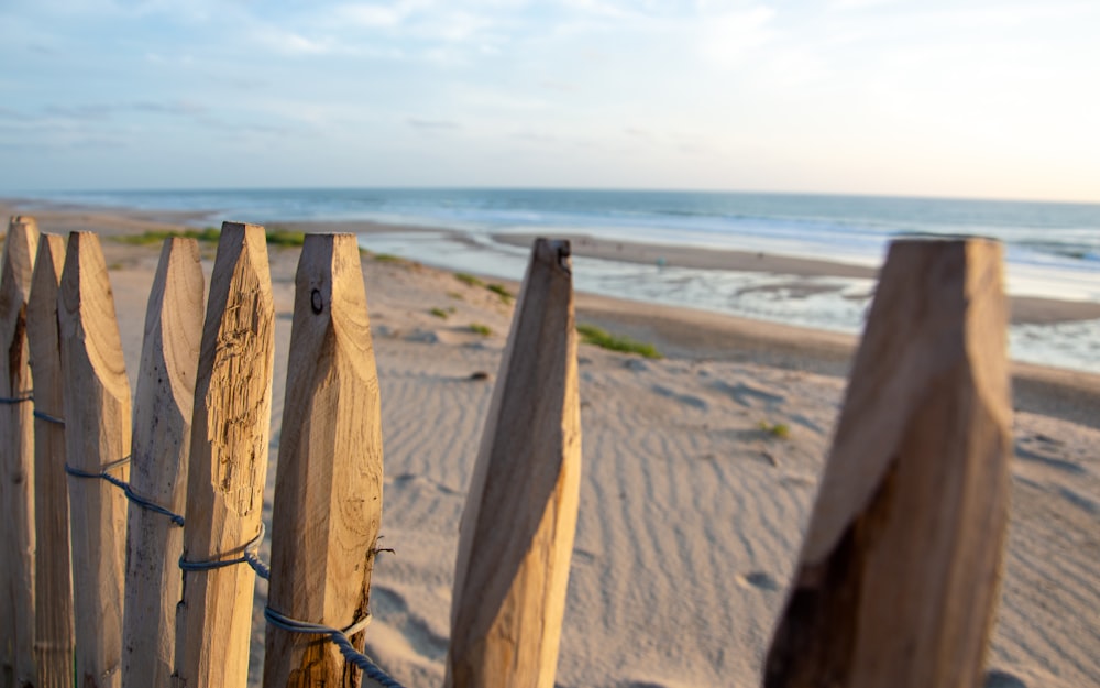 a wooden fence on a beach with the ocean in the background