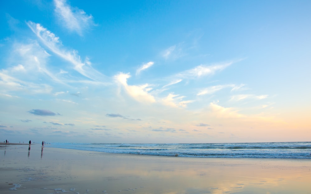 a couple of people standing on top of a sandy beach