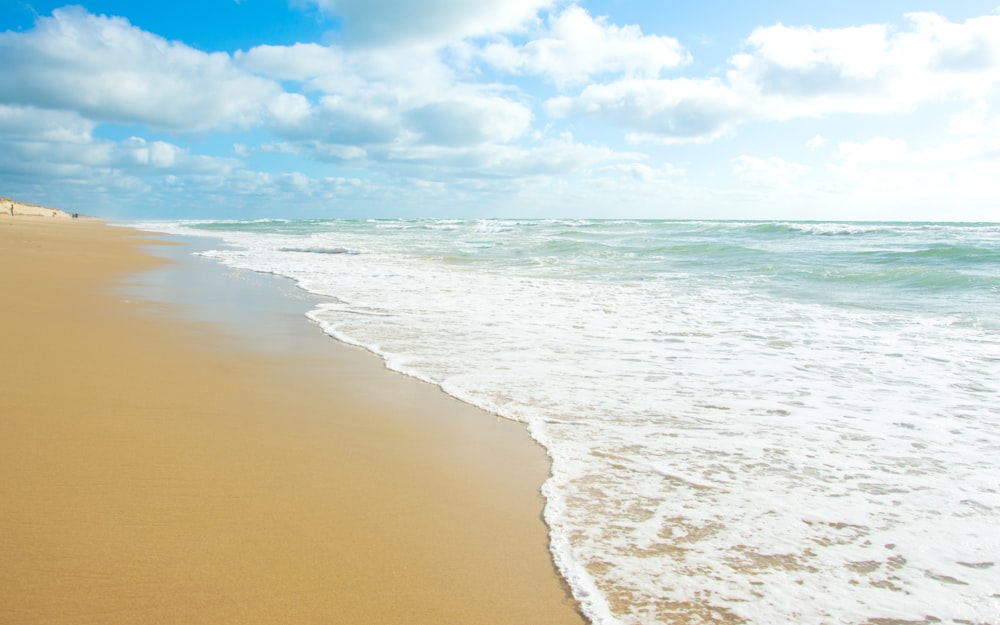 a sandy beach with waves coming in to shore