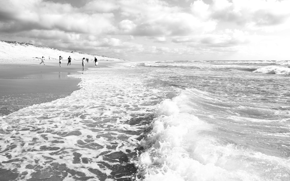 a group of people standing on top of a beach next to the ocean