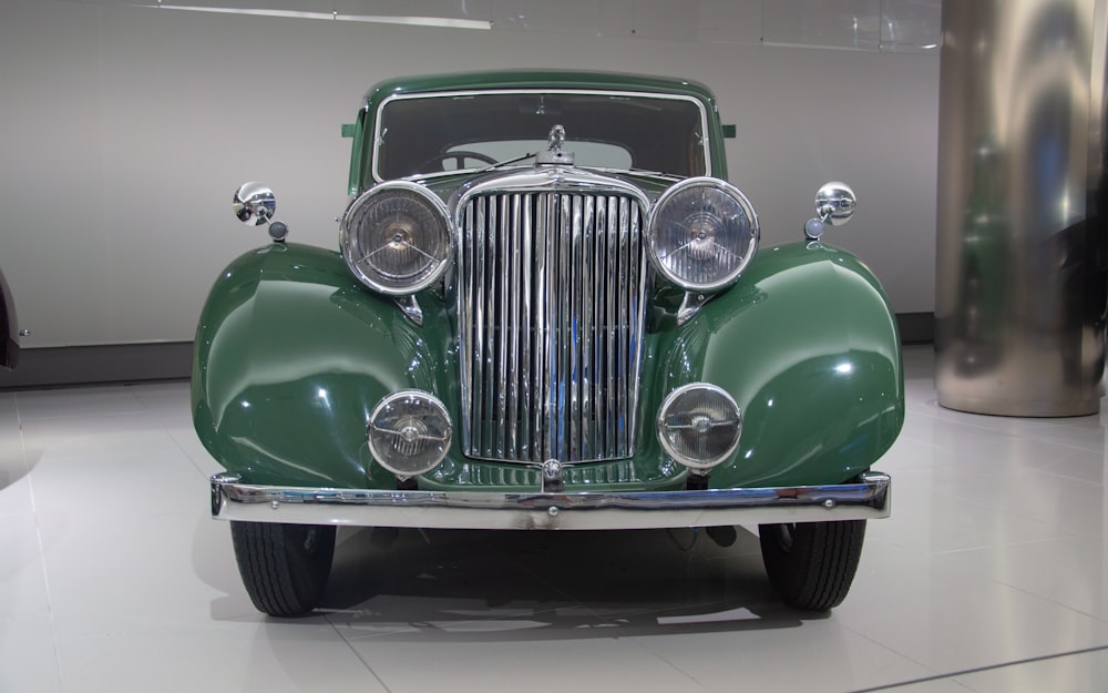 an old green car is on display in a museum