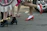 Close-up of a pair of vibrant magenta shoes walking confidently on a city sidewalk.