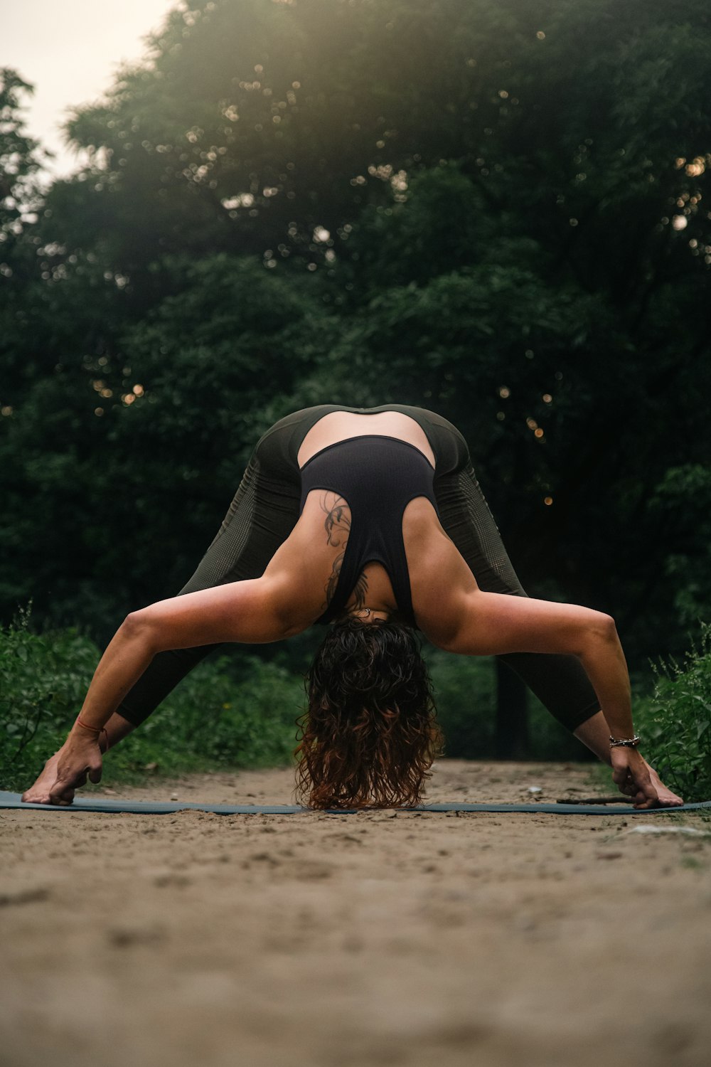 a woman is doing a yoga pose in a park