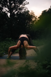 a woman is doing a yoga pose in the woods