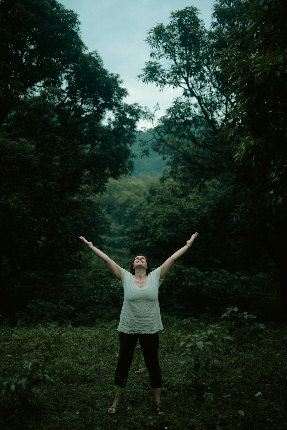 a woman standing in the middle of a forest