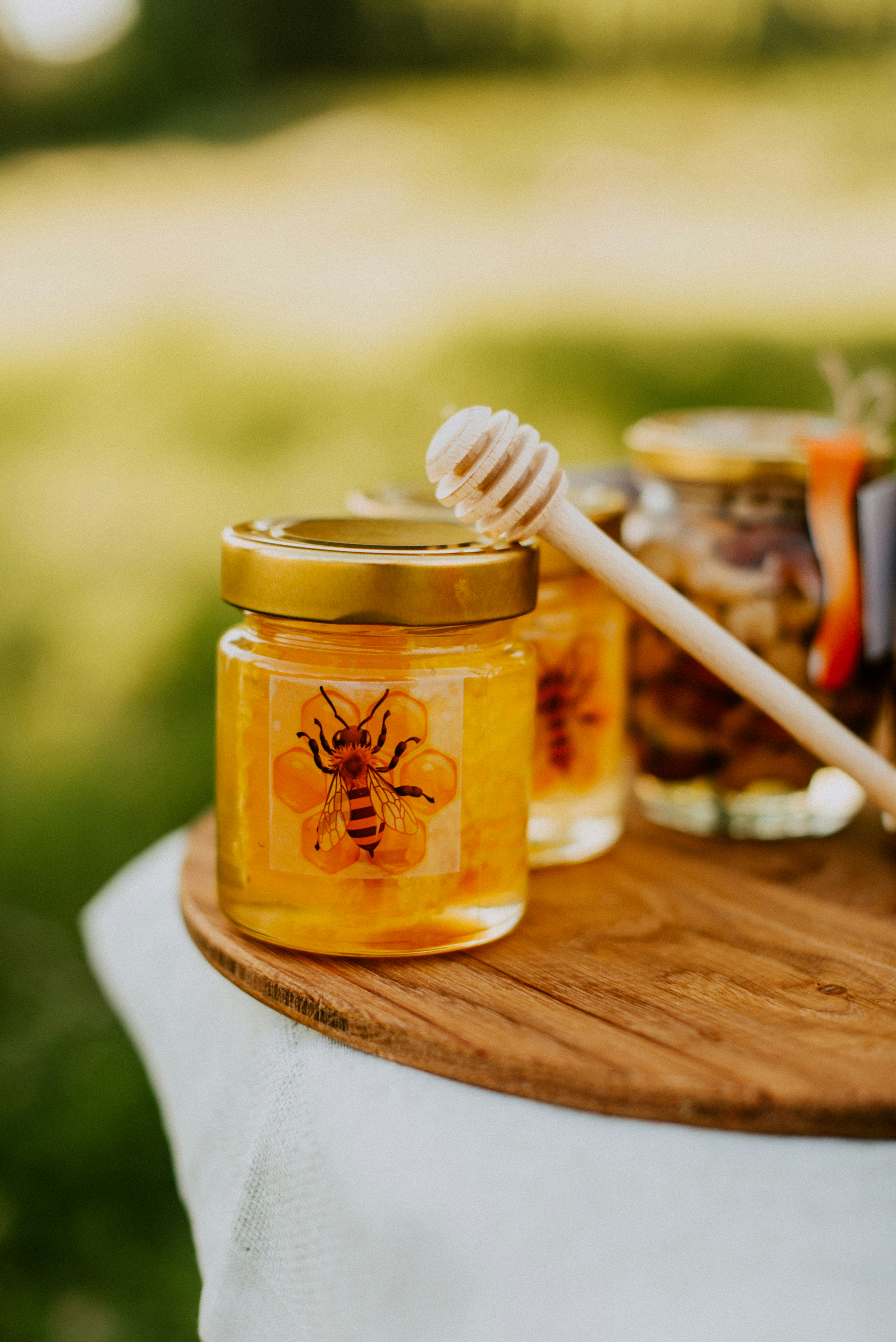 Glass jars of golden honey and colorful fruit jams arranged on rustic wooden board