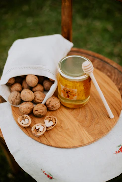 a wooden table topped with a jar of honey and nuts