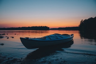 A peaceful kayak resting on the shore of a crystal-clear lake at sunset in Bariloche