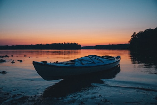 A peaceful kayak resting on the shore of a crystal-clear lake at sunset in Bariloche