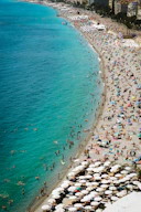 A crowded beach scene with families enjoying the sun and surf.