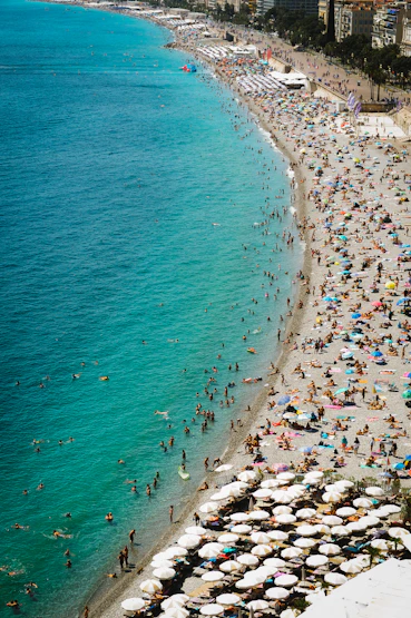 A crowded beach scene with families enjoying the sun and surf.