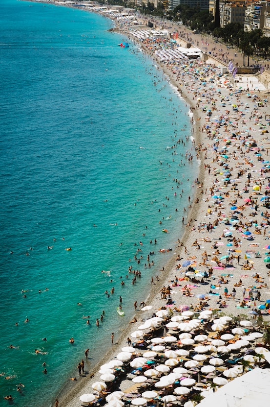 a crowded beach filled with people and umbrellas in Nice