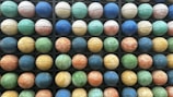 A grid of colorful basketballs arranged in an organized manner, showcasing a variety of hues such as blue, green, orange, and yellow. Each basketball is positioned within a compartment, creating a pattern across multiple rows and columns.