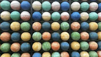 Close-up image of colorful kids mini volleyballs arranged on a gym floor.