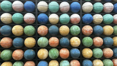 A neatly arranged display of basketballs, footballs, and volleyballs in monochrome tones.