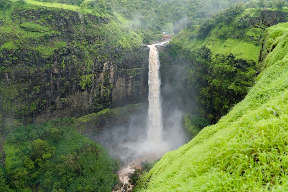 a large waterfall in the middle of a lush green valley