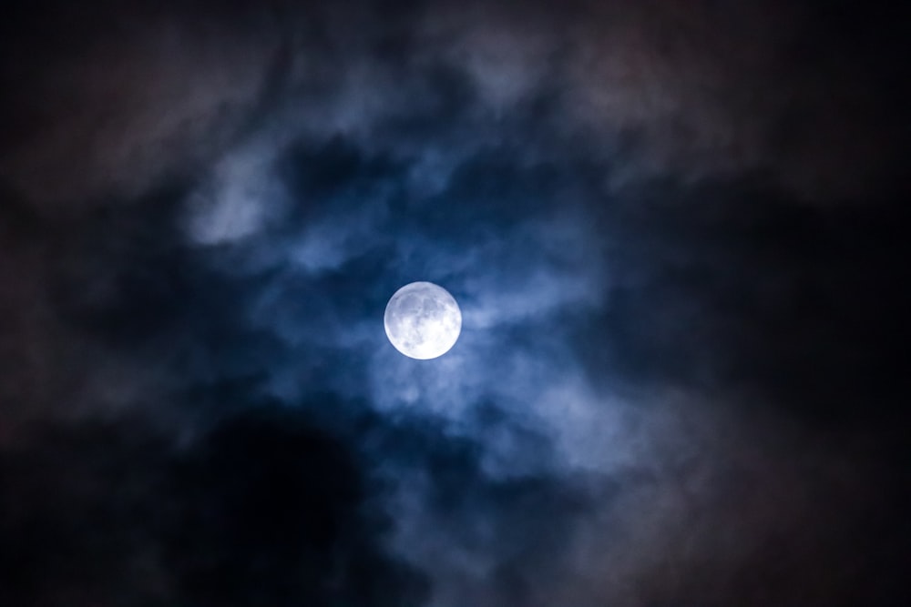 a full moon is seen through the clouds