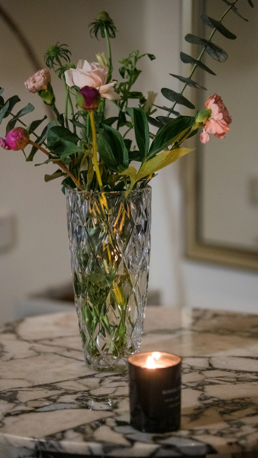 a vase of flowers on a table with a candle