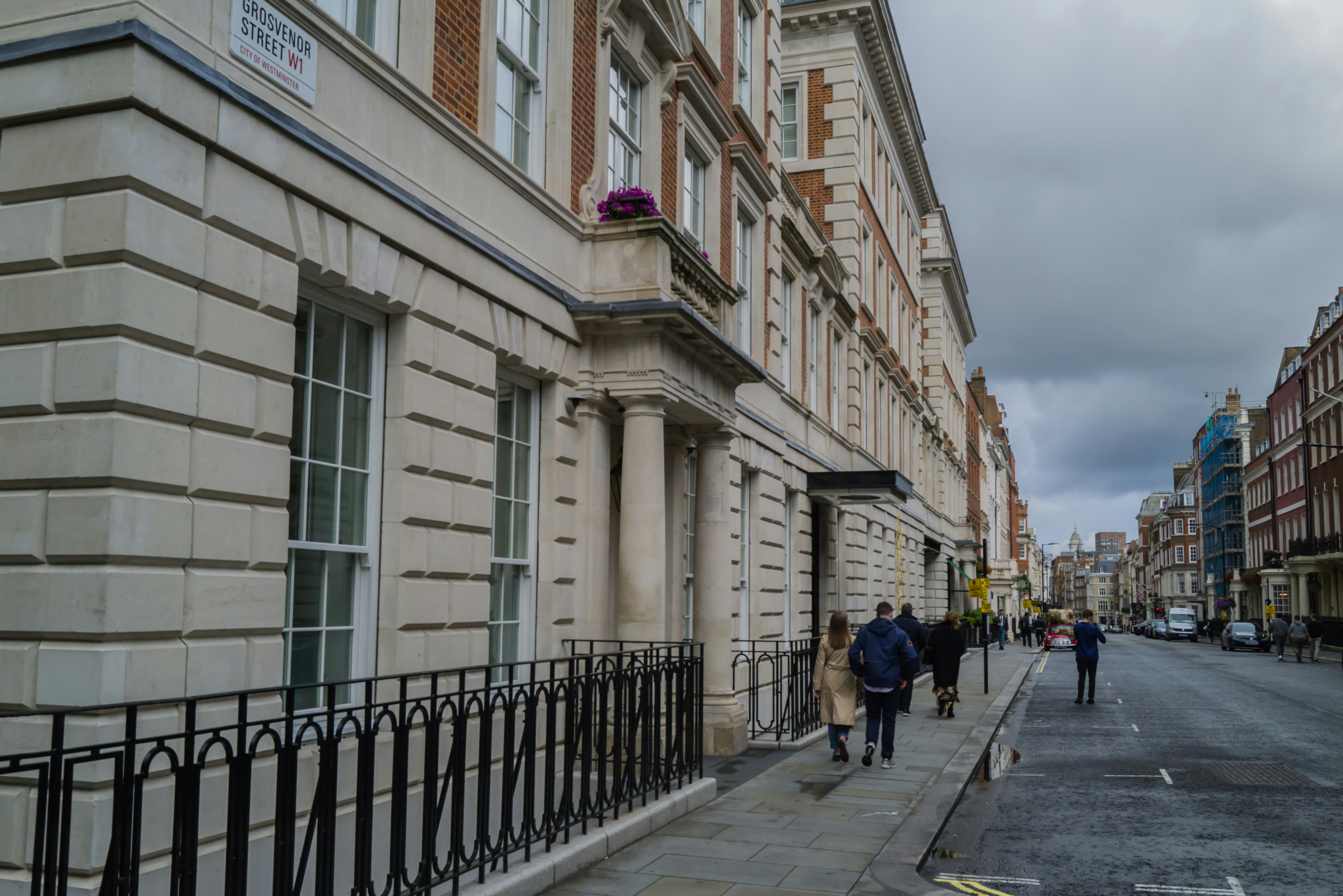 a group of people walking down a street next to tall buildings