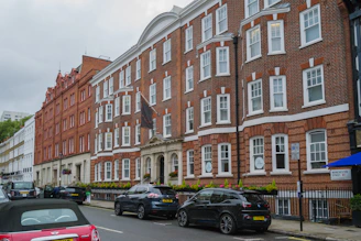 cars parked on the side of the road in front of a row of brick buildings