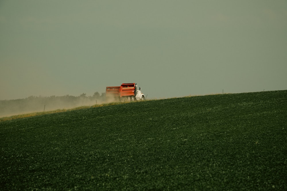 a red truck driving across a lush green field