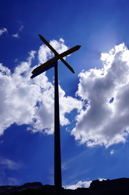 A bright, welcoming crossroads signpost surrounded by soft amber light against a deep navy sky.