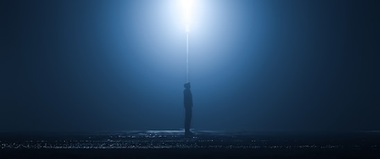 A shadowy figure standing under a flickering streetlamp on a foggy night, evoking suspense and mystery.