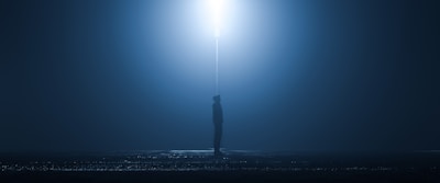 A shadowy figure standing under a flickering streetlamp on a foggy Memphis street at night.