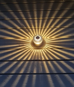 Close-up of a sleek wall-mounted light fixture casting artistic shadows on a textured wall.