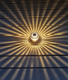 Close-up of a sleek wall-mounted light fixture casting artistic shadows on a textured wall.