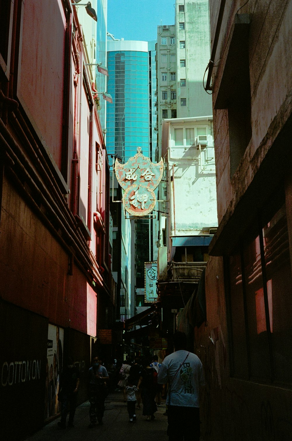 a group of people walking down a street next to tall buildings