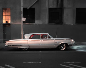 A gleaming vintage car parked under neon lights with a starry space-themed mural in the background.