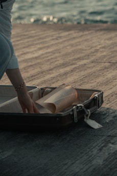 a person putting a roll of paper in a suitcase