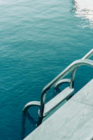 A vintage pool ladder emerging from crystal-clear water surrounded by lush greenery.